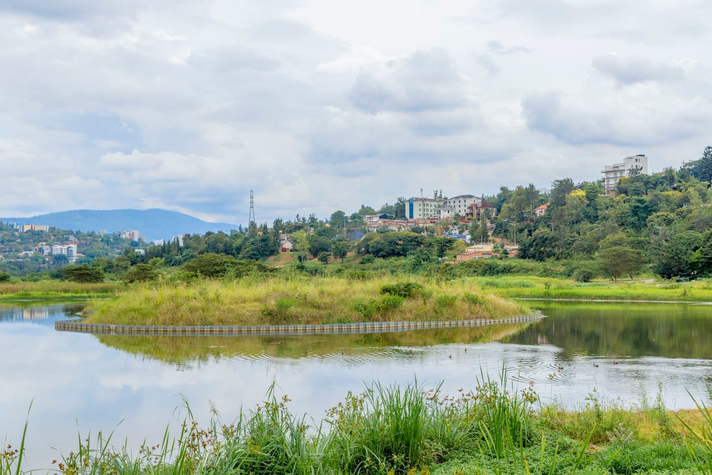 Lake with grassy island and buildings on a distant hill