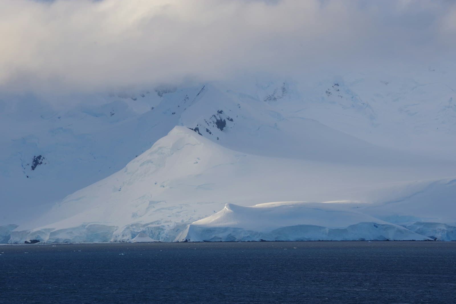 Snow-covered mountains rise above the ocean